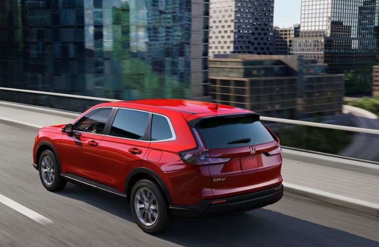 The red color 2024 CR-V Hybrid is running on the road.